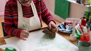 A lady prints wrapping paper using homemade stamps and paint