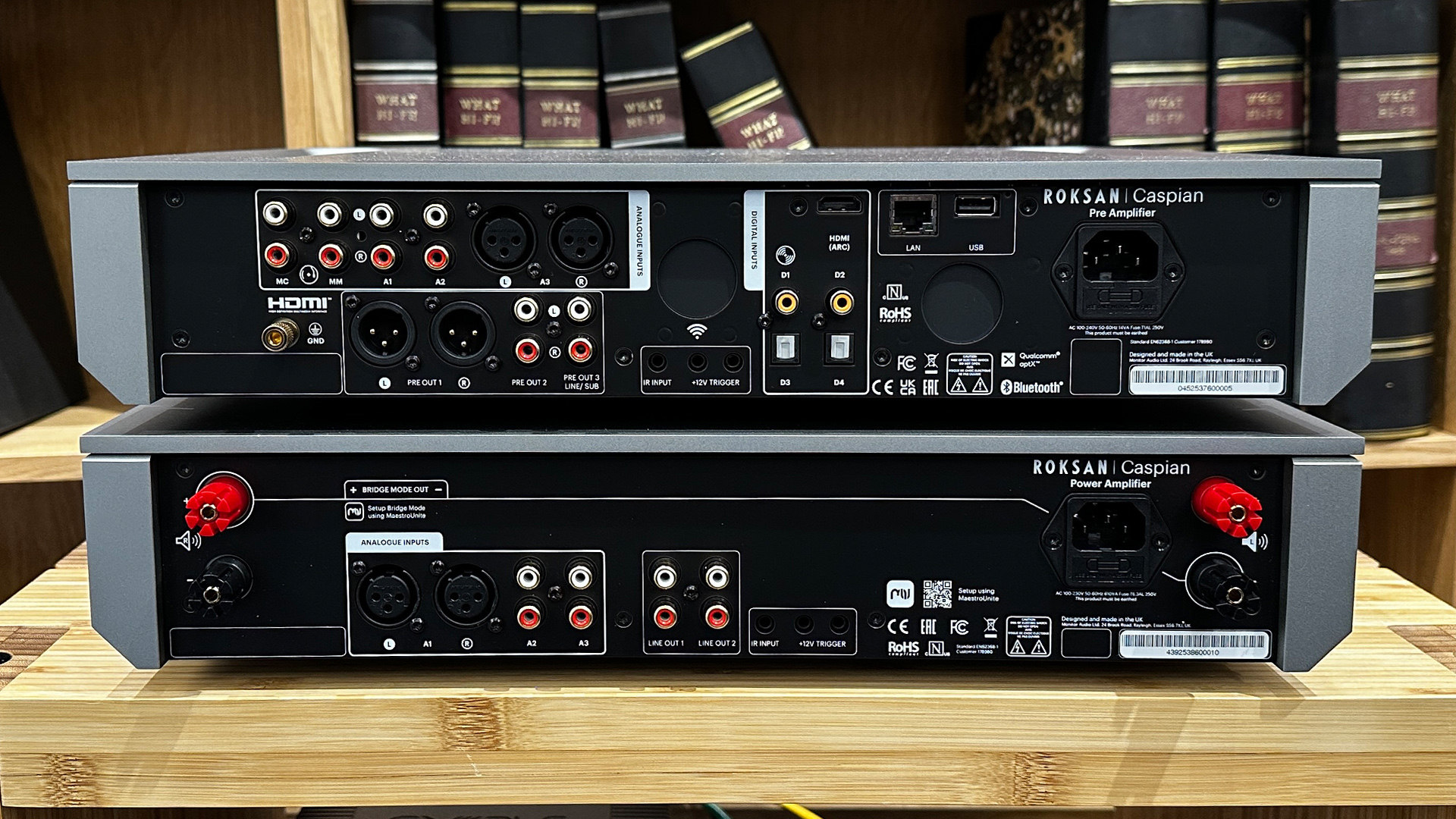 Roksan Caspian 4G Streaming Pre-Amplifier/Caspian 4G Power Amplifier on wooden hi-fi rack in front of bookcase, rear of units showing connections
