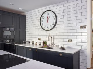 living room with white metro tiles and dark interior scheme by Higham Furniture