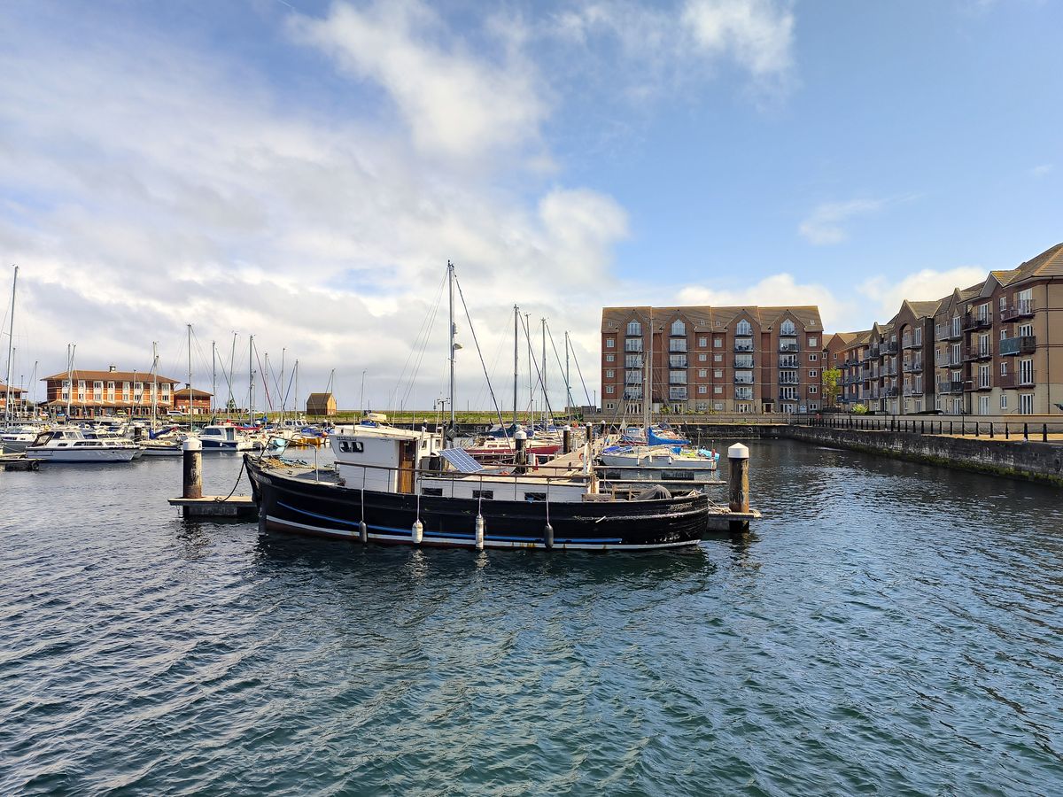 A marina or harbor scene with boats moored in calm water on a sunny day