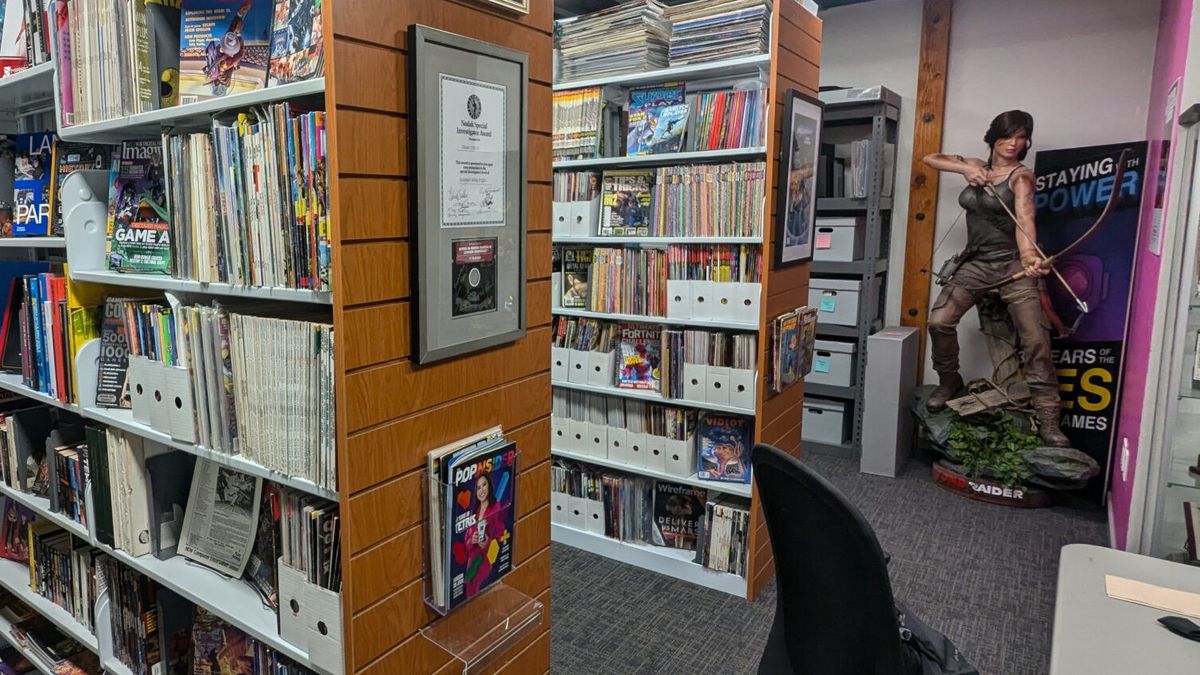 An image of the Video Game History Foundation&#039;s physical library, showing rows of bookshelves filled with old magazines, and a life-size statue of Lara Croft in the far right corner