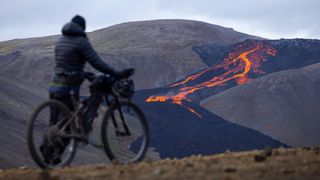Lael Wilcox looks at an erupting volcano in the distance