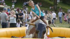 Here, a young boy rides a mechanical bull during the annual Ambleside Sports competition at Rydal Park in the Lake District.