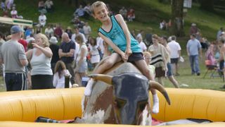Here, a young boy rides a mechanical bull during the annual Ambleside Sports competition at Rydal Park in the Lake District.