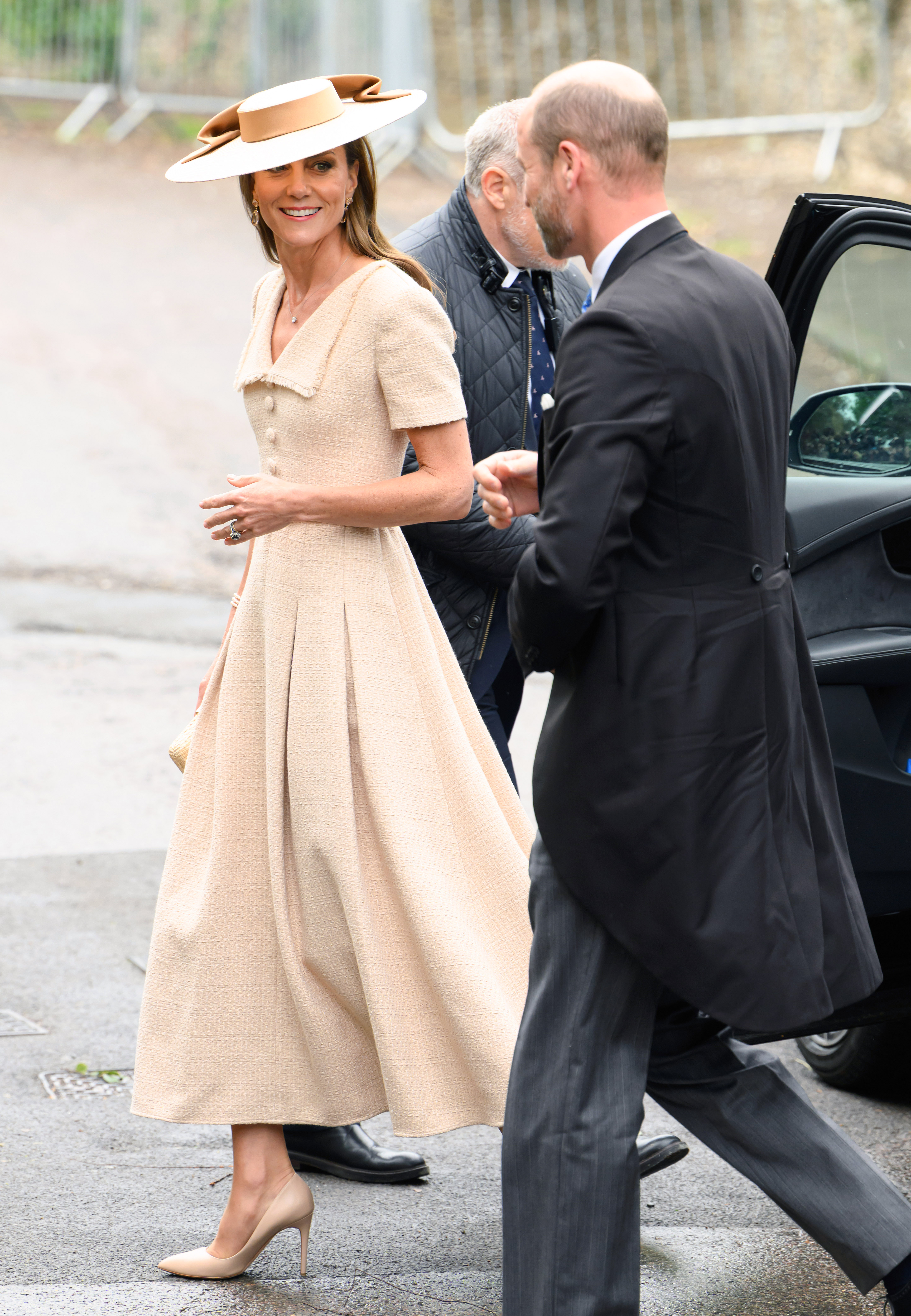 Princess Kate wearing a beige dress and hat walking next to Prince William at Peter Phillips and Harriet Sperling's wedding