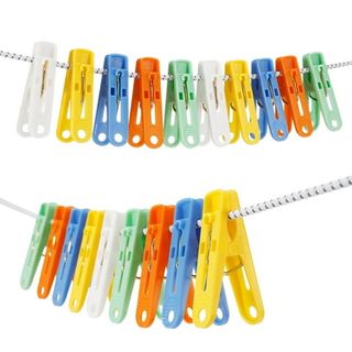 A collection of multi colored yellow, orange, green, blue, and white plastic clothes pegs on a white cotton clothes line. 