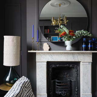 Victorian fireplace with marbled mantelpiece, grey panelled walls and large circular mirror. Renovation and interior design of a Georgian townhouse in East London, by Emilie Fournet of Emilie Fournet Interiors