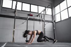 A woman in a gym performing mountain climbers 