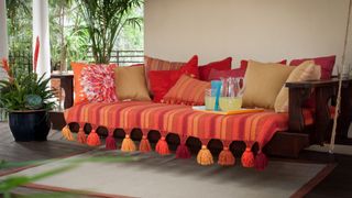 A seat covered in fringed throws and cushions