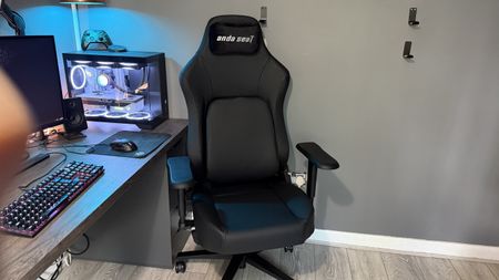 The AndaSeat Phantom 4 Pro in a brightly lit home office environment in front of a gaming PC.