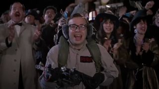 Rick Moranis holds a proton wand overjoyed in front of a crowd in Ghostbusters II.