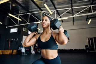 A woman squatting with two weights