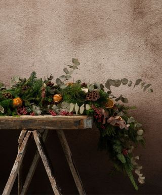 A rustic side table with a large real pine garland decorated with dried fruits