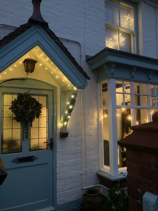 a lit up Christmas porch with a wreath on the door