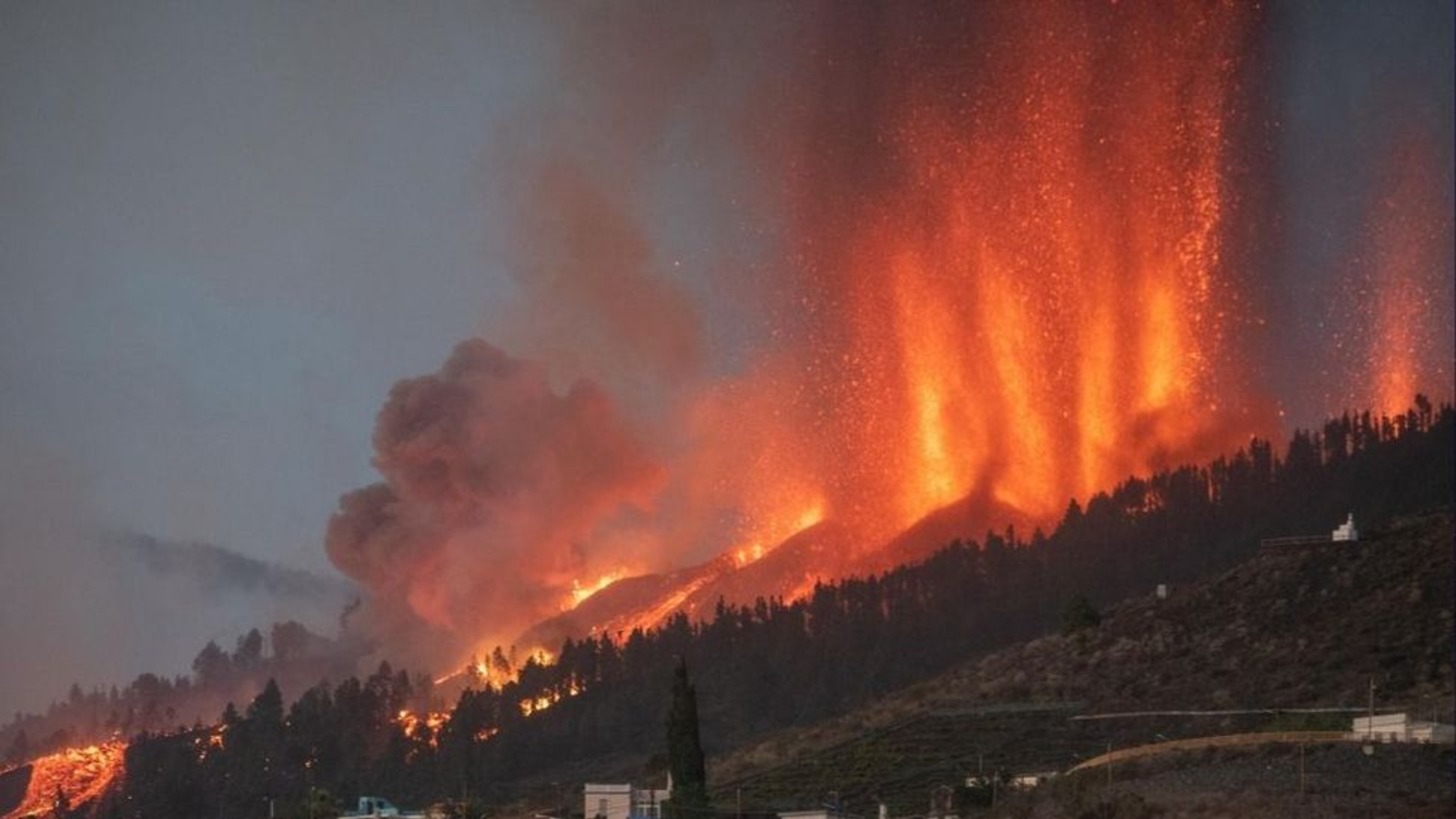 Photo of giant fountains of lava shooting out of the ground on the slopes of a mountain