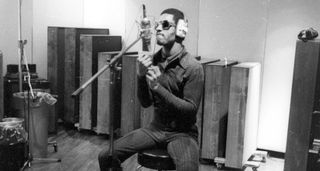 A black and white image of Stevie Wonder sitting on a stool to record harmonica for Talking Book at Electric Lady Studios, 1972