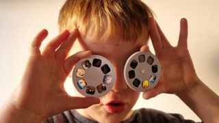 Photo of a young boy holding the slide projector disks up to his face
