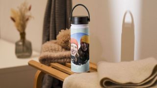 A personalised water bottle features a photo of two grinning female friends wearing bobble hats.