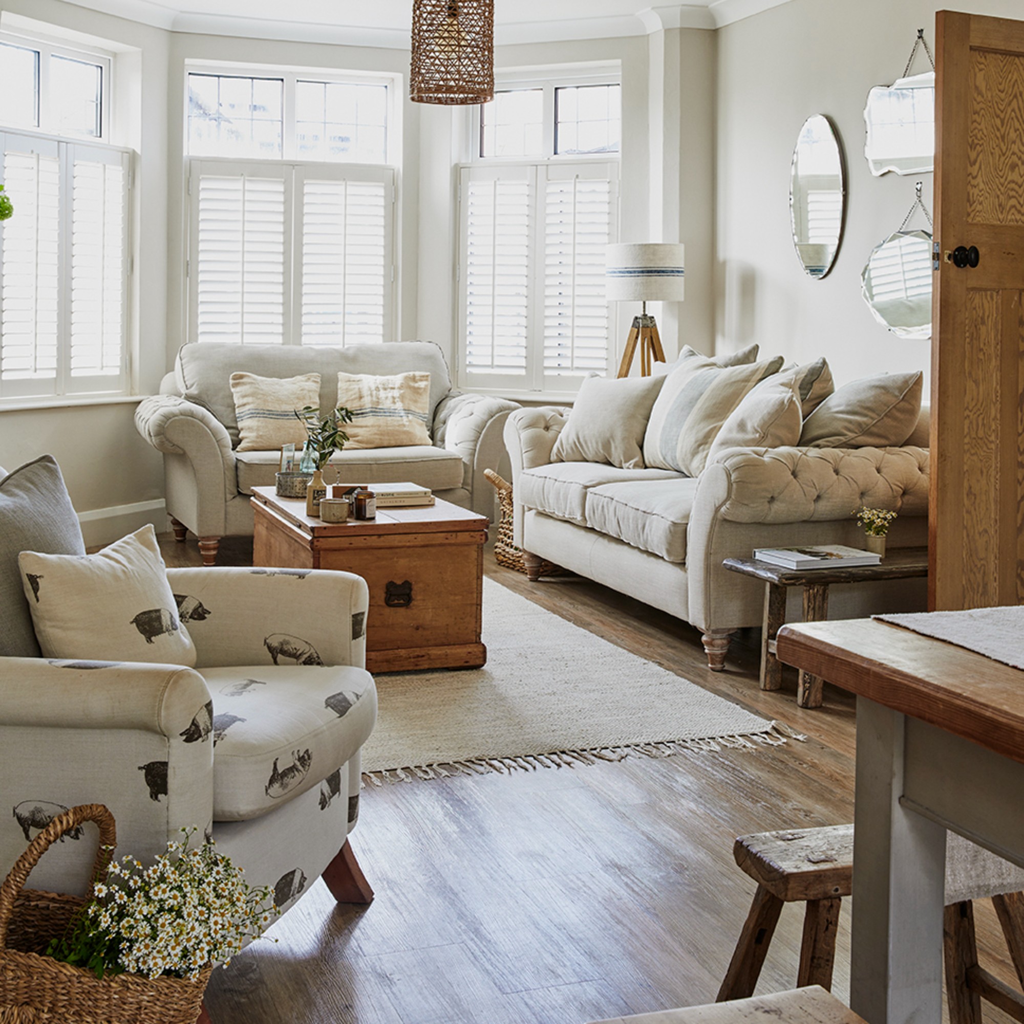 A neutrally coloured open-plan living room in a rustic farm house style with a chest used as a coffee table