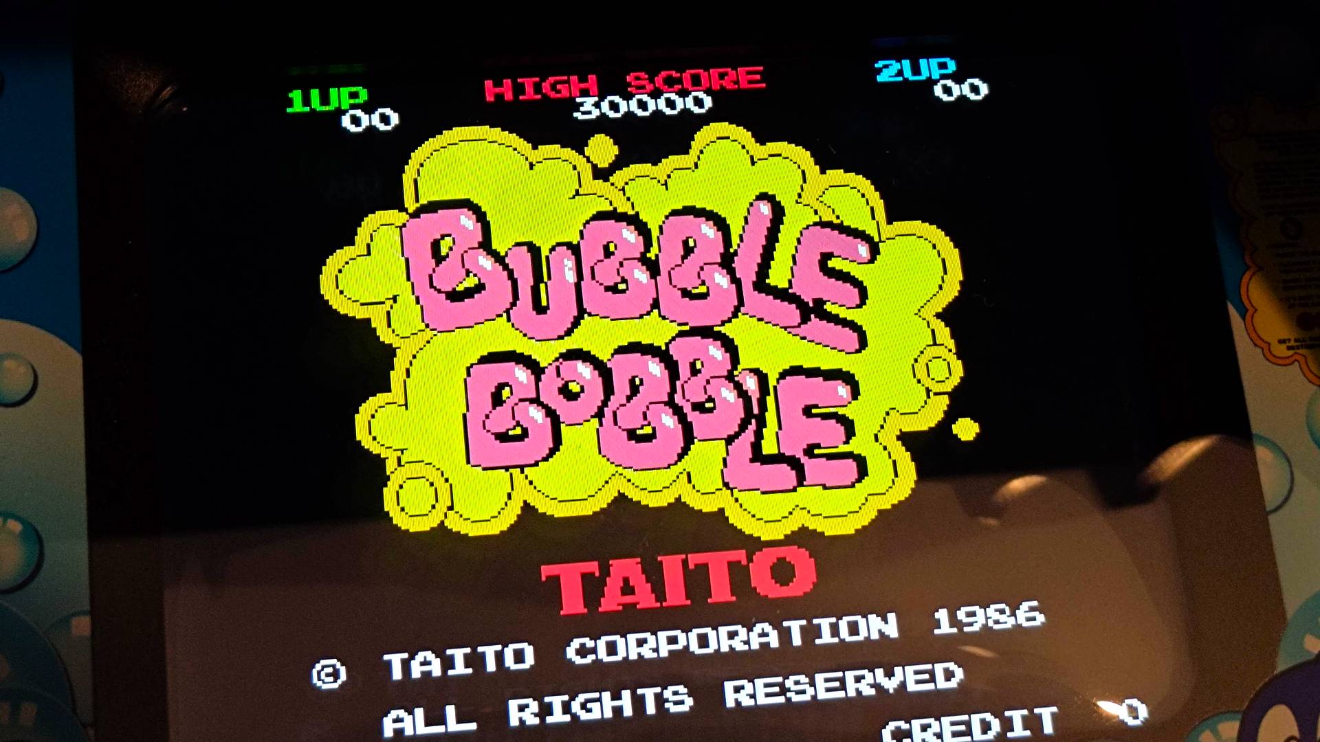 Un primer plano de la máquina arcade Quartercade Taito Bubble Bobble con el nombre del juego mostrado