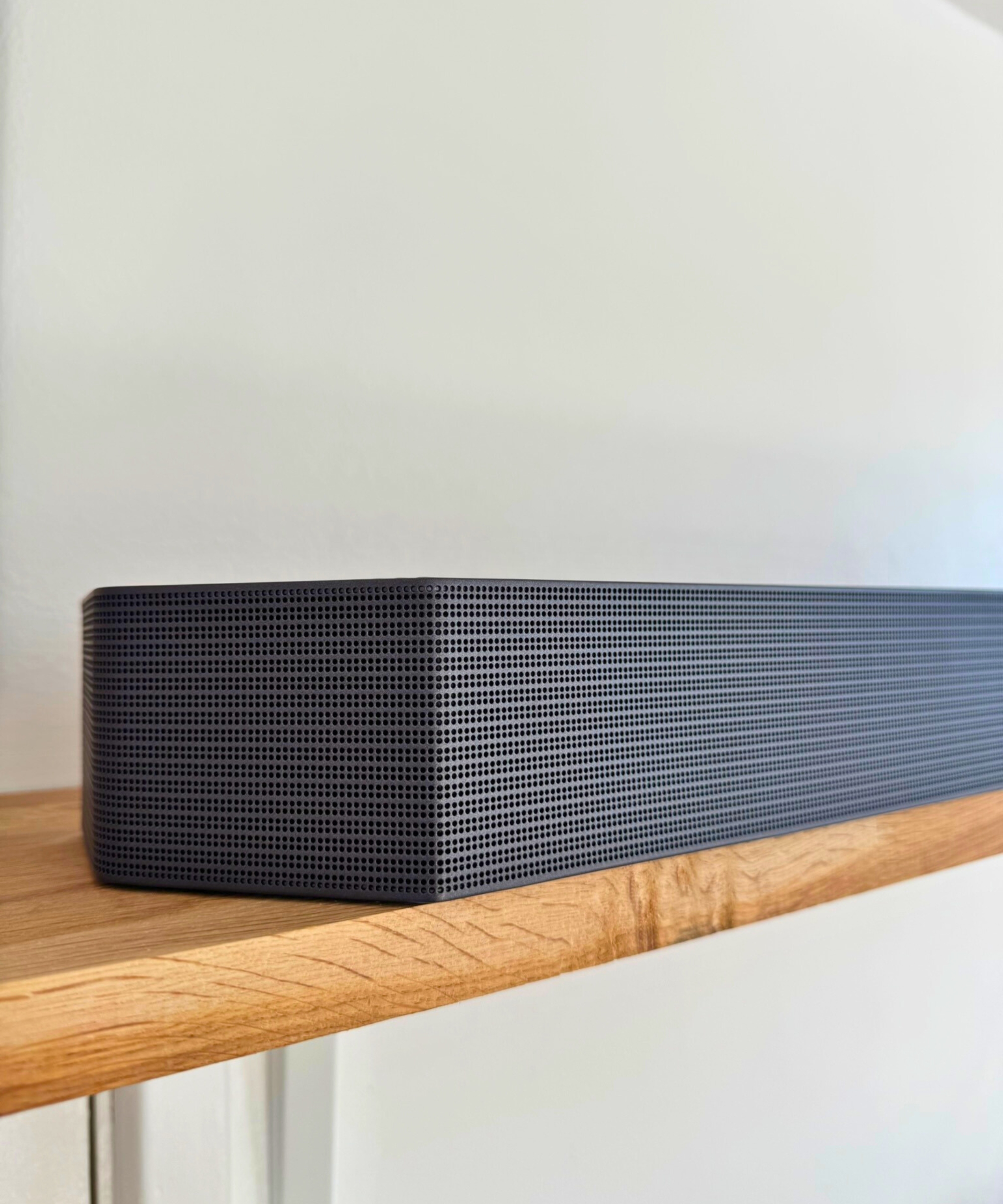 Samsung HW-Q990F soundbar on wooden shelf.