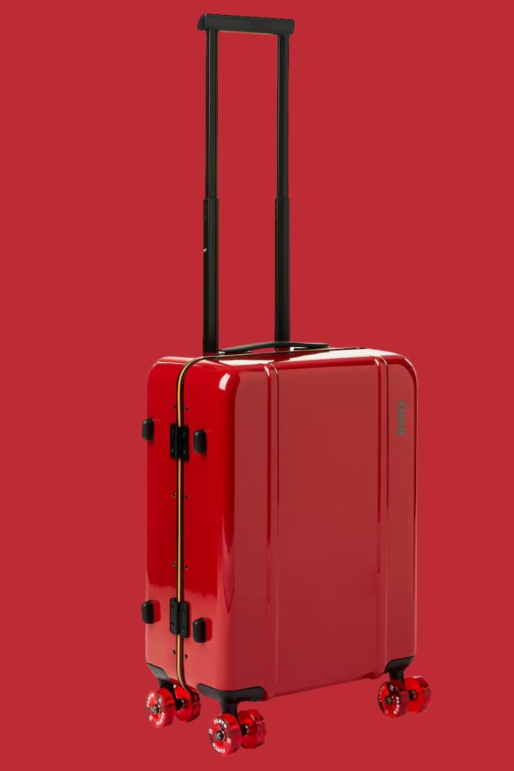 FLOYD cabin carry-on in polished red against red background.