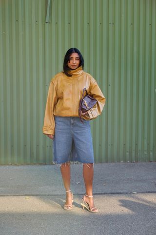 Woman in jacket with funnel neck and long denim shorts