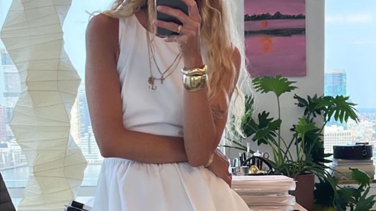 Olympia Gayot posing in front of mirror with white tank and white skirt 