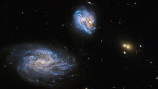 three galaxies hang in space with smaller ones about