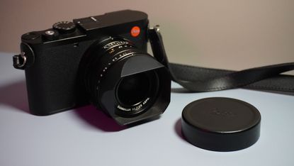 The Leica Q3 camera on a grey and pink background