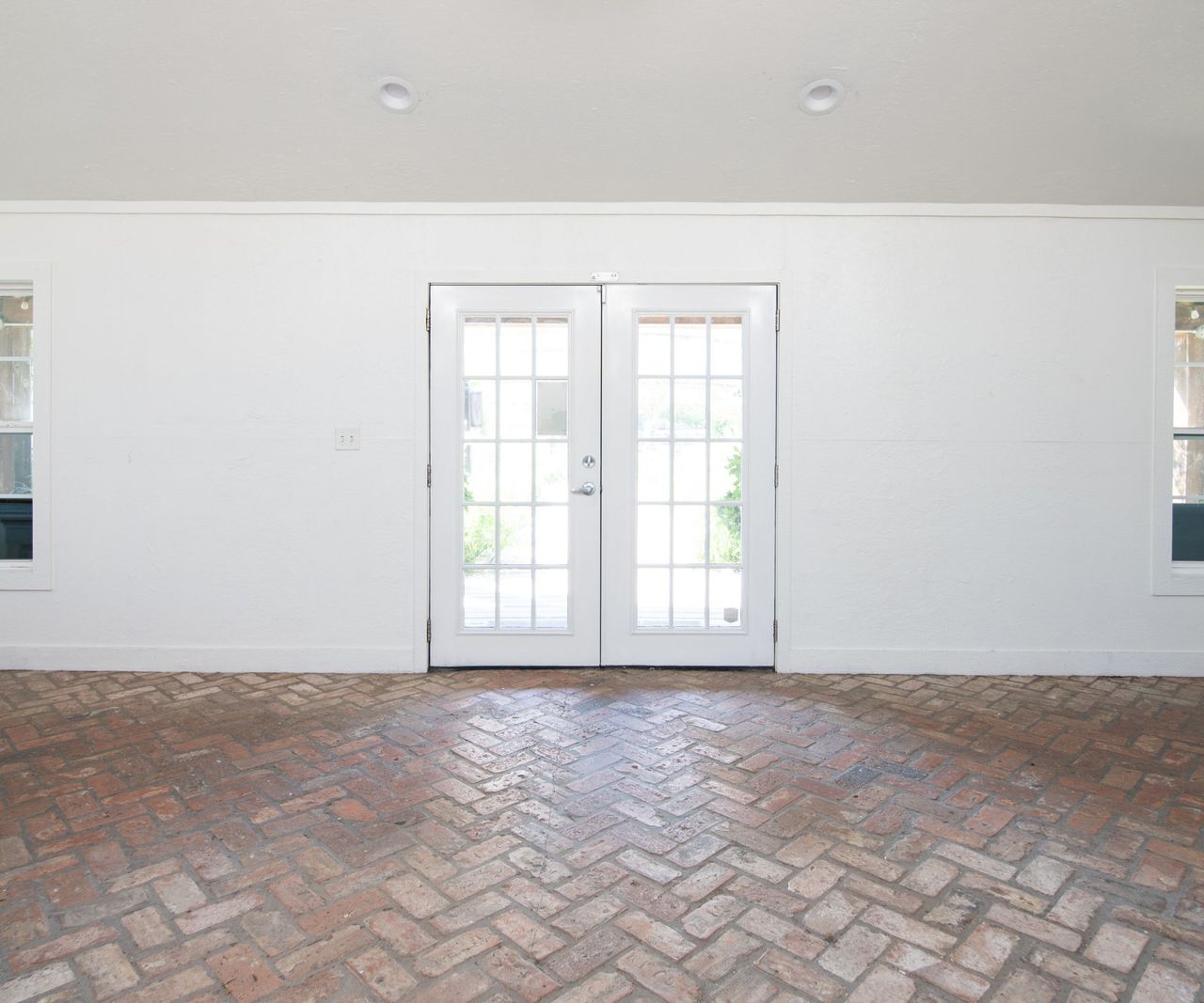 White room with brick floor and glass doors