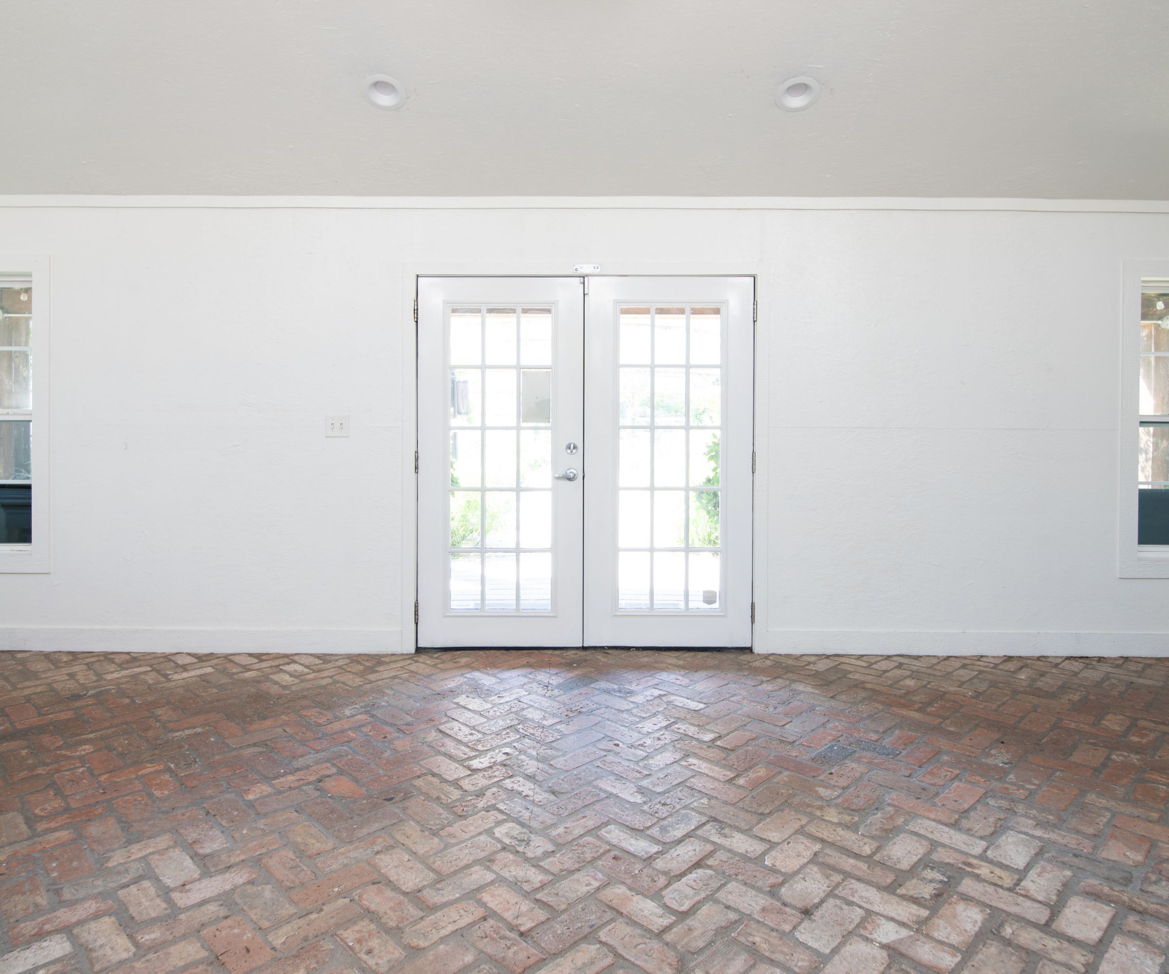 White room with brick floor and glass doors