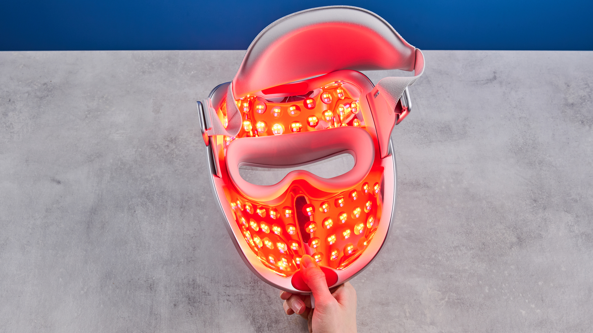 the ulike reglow led skincare mask showing its red LED light and control and charger