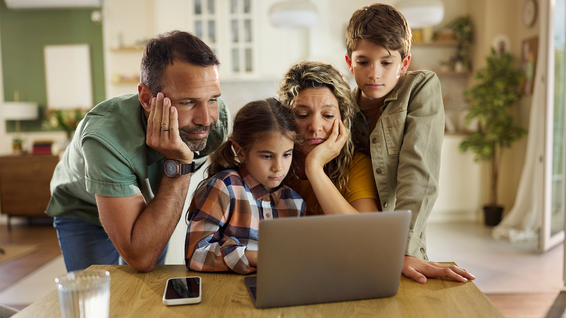 Displeased parents and their kids reading a problematic e-mail on a computer at home.