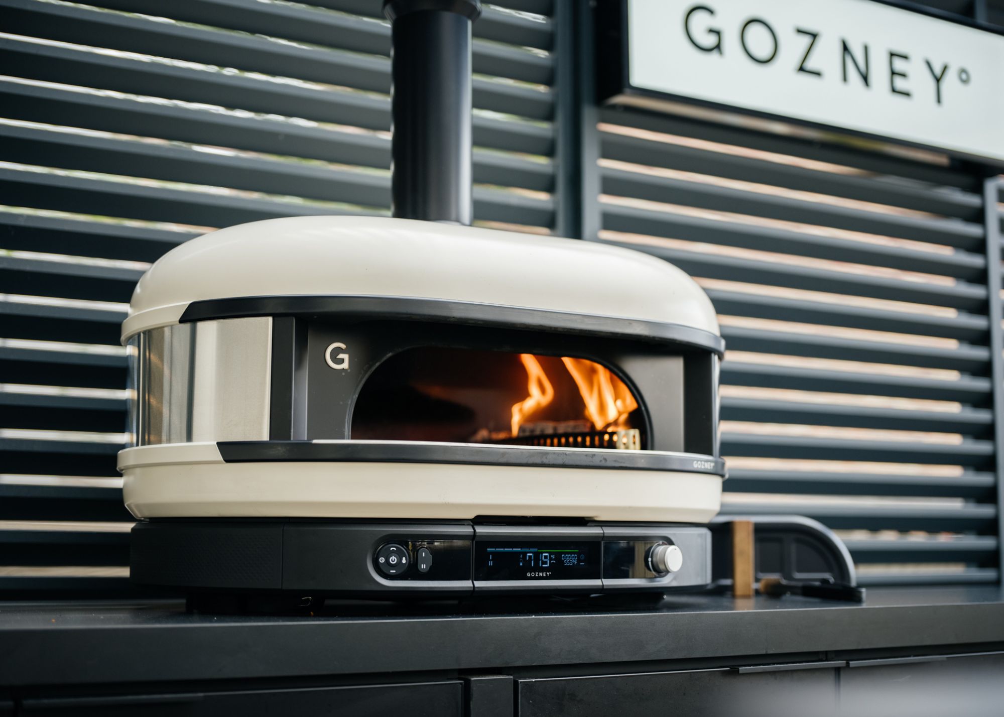 Gozney's Dome XL Gen 2 with Gozney branding in the background against dark gray shutters