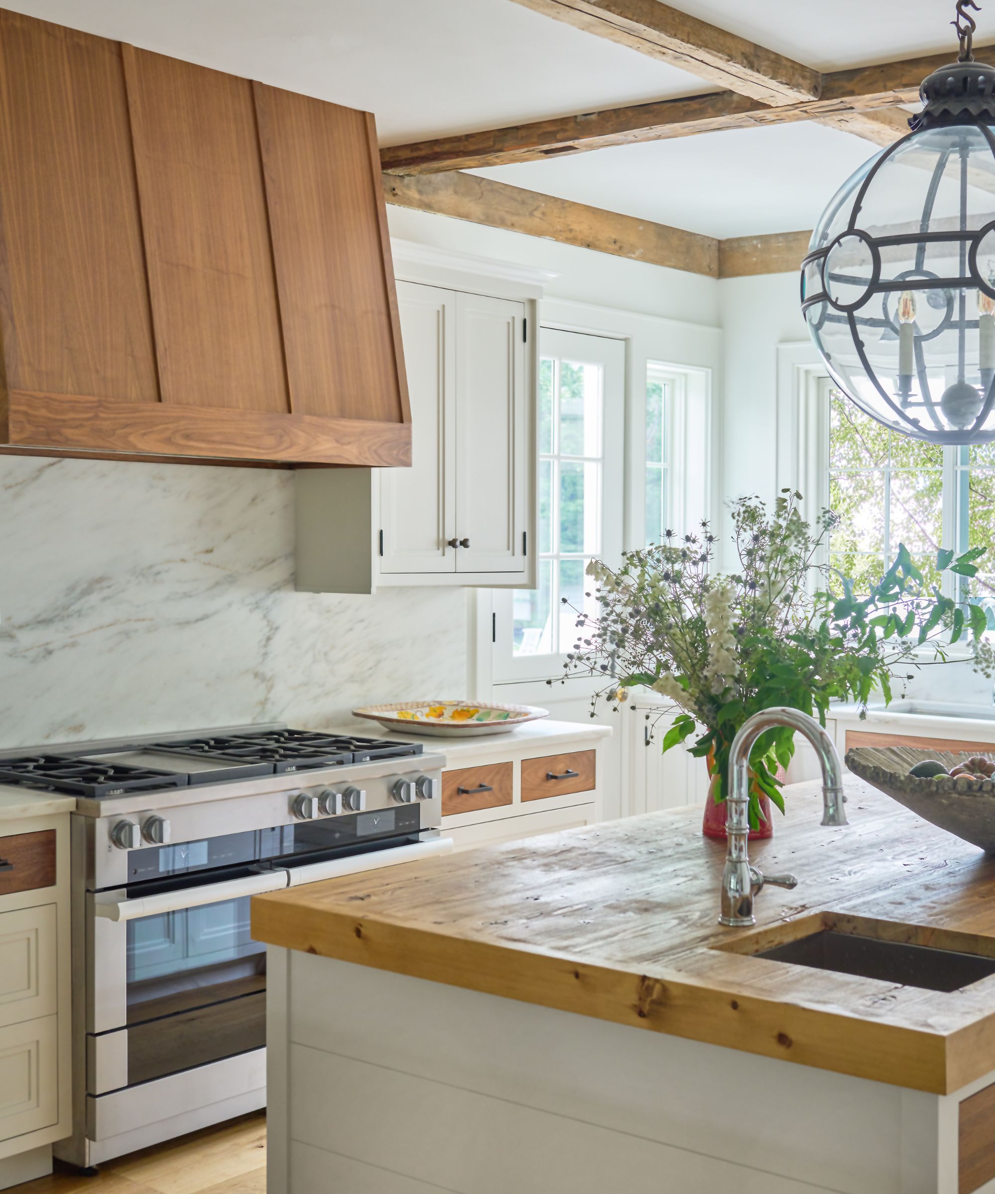 White kitchen with wooden topped island and marble splashback