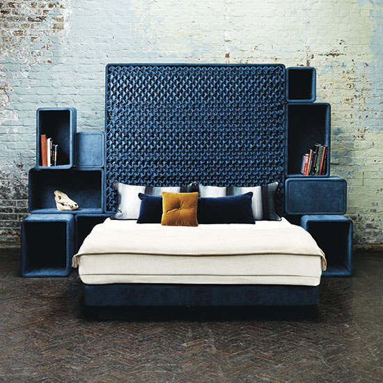 bedroom with brick wall blue bed and wooden flooring