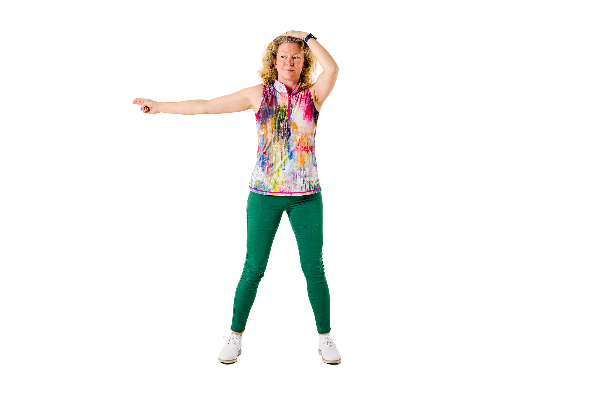 Katie Dawkins demonstrating a progression of the shoulder turn drill, with her left hand on her head and right arm outstretched as she turns the upper body