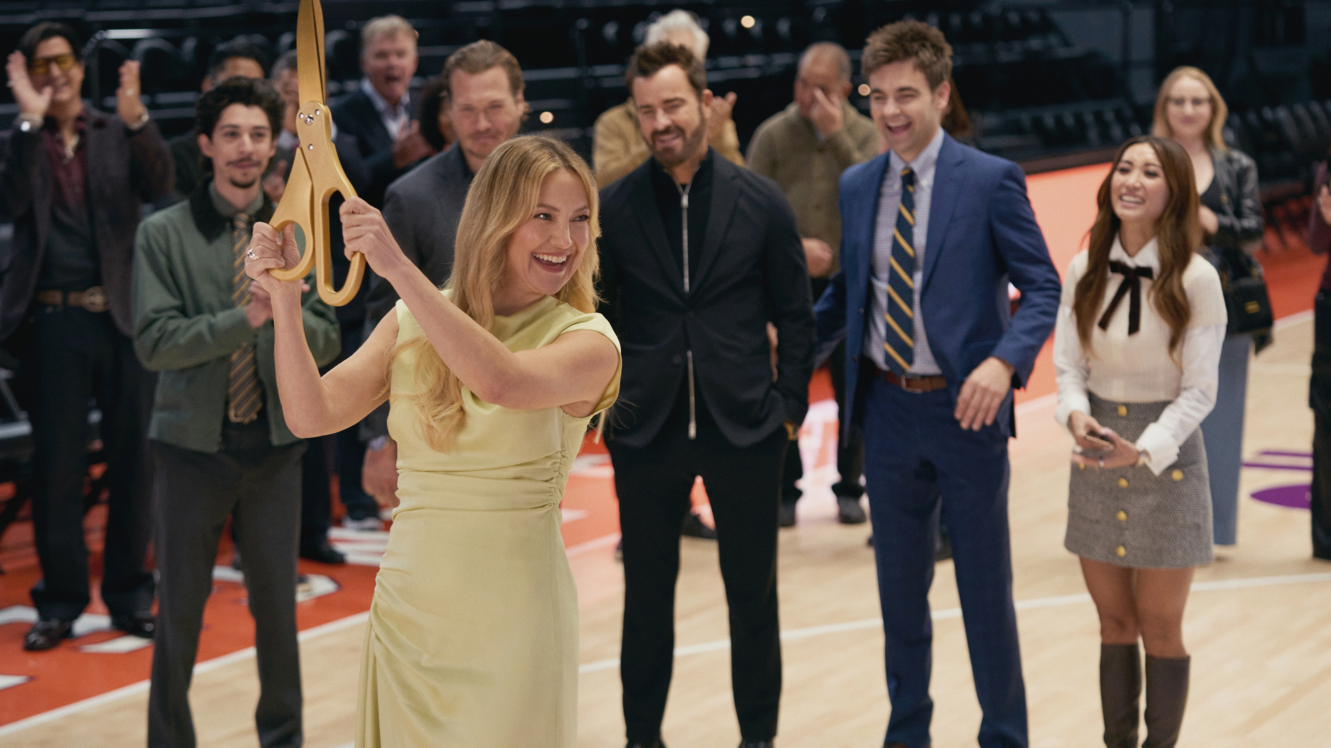 Kate Hudson as Isla Gordon holds giant gold scissors on a basketball court. Also seen Fabrizio Guido as Jackie, Scott MacArthur as Ness, Justin Theroux as Cam, Drew Tarver as Sandy, and Brenda Song as Ali