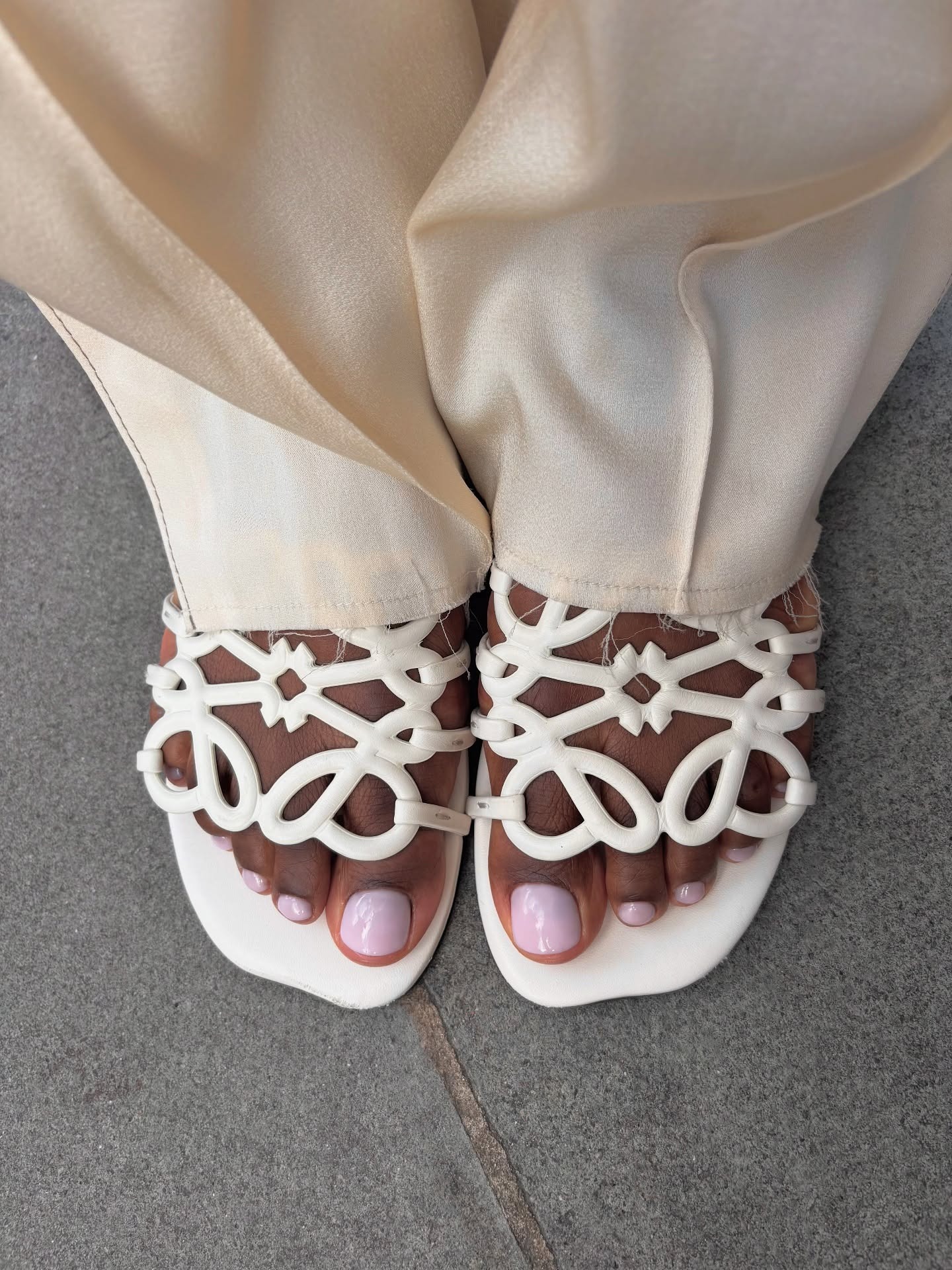 Lilac pedicure on feet, wearing white Loewe sandals