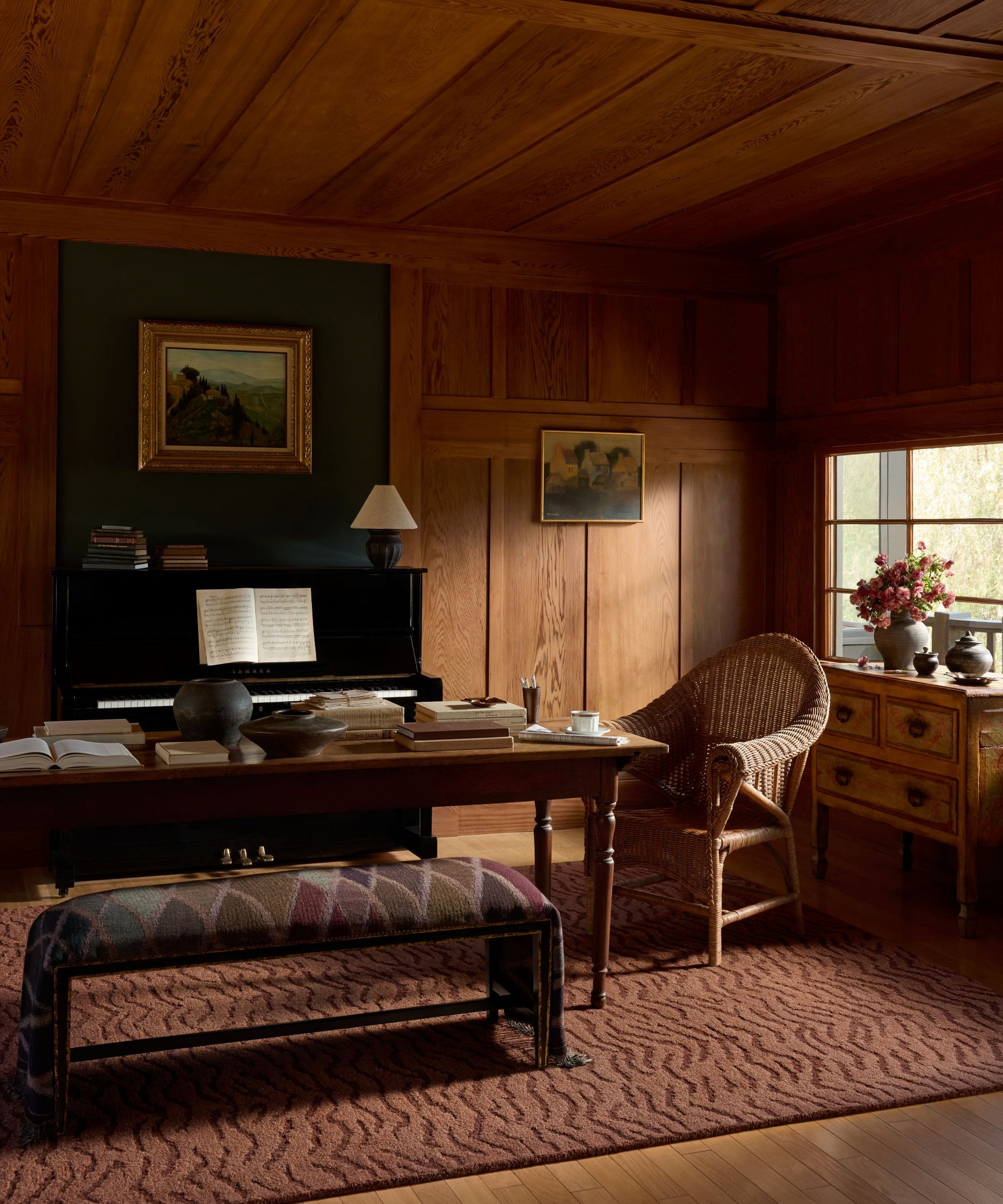 a wood-paneled study room with a animal-printed rug, a wicker chair, and a large table