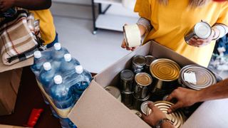 People volunteering by packing cans into a box for a foodbank