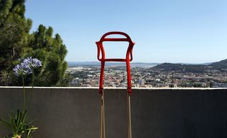 Red chair frame next to a balcony outside over looking the city