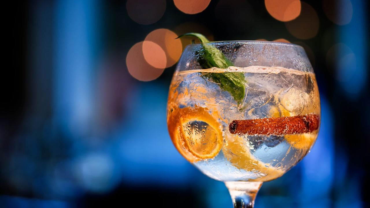 Glass of gin on bar counter with blurred background in shades of blue and boke. - stock photo