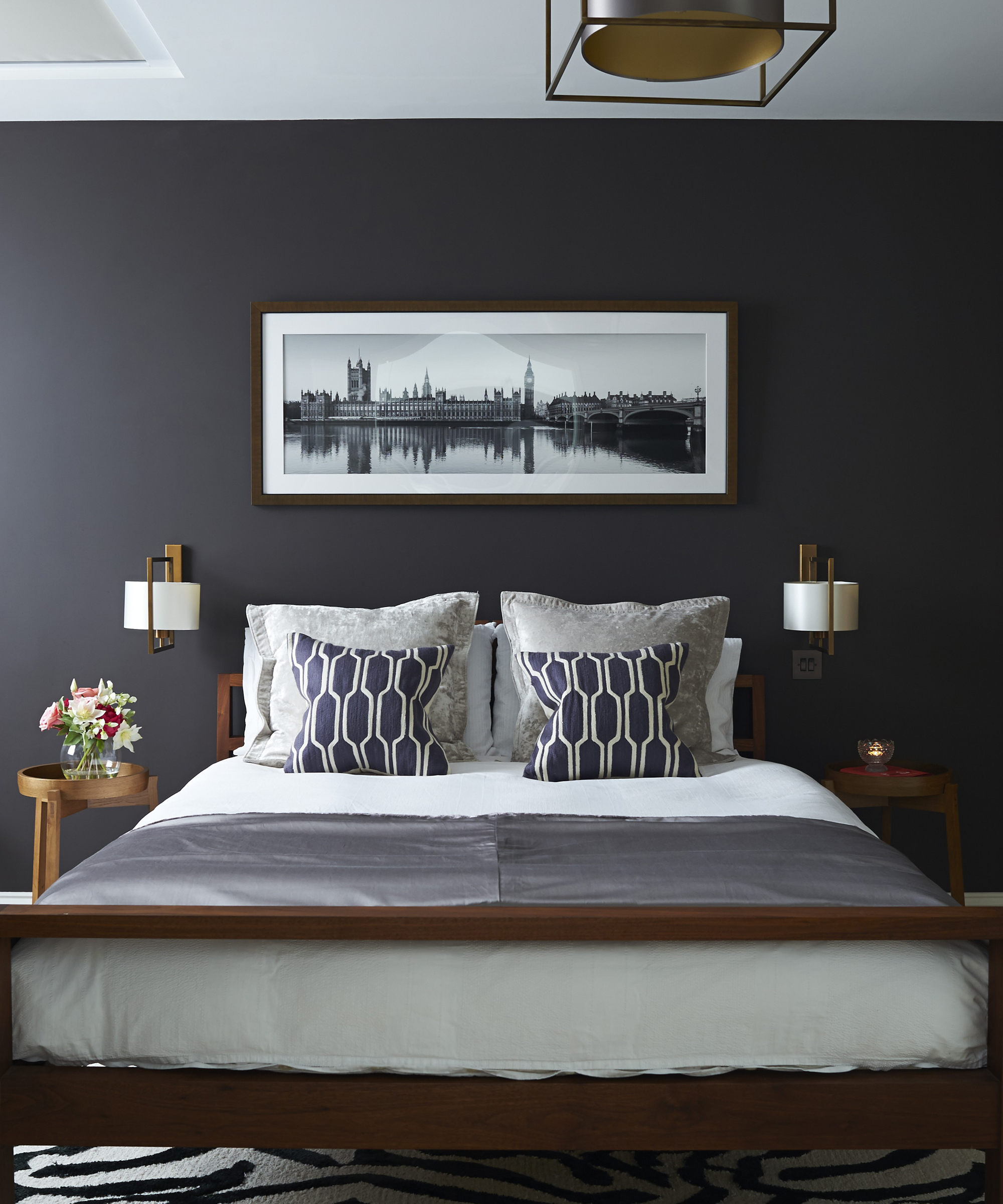 A grey bedroom idea with dark walls, white linen and black accessories