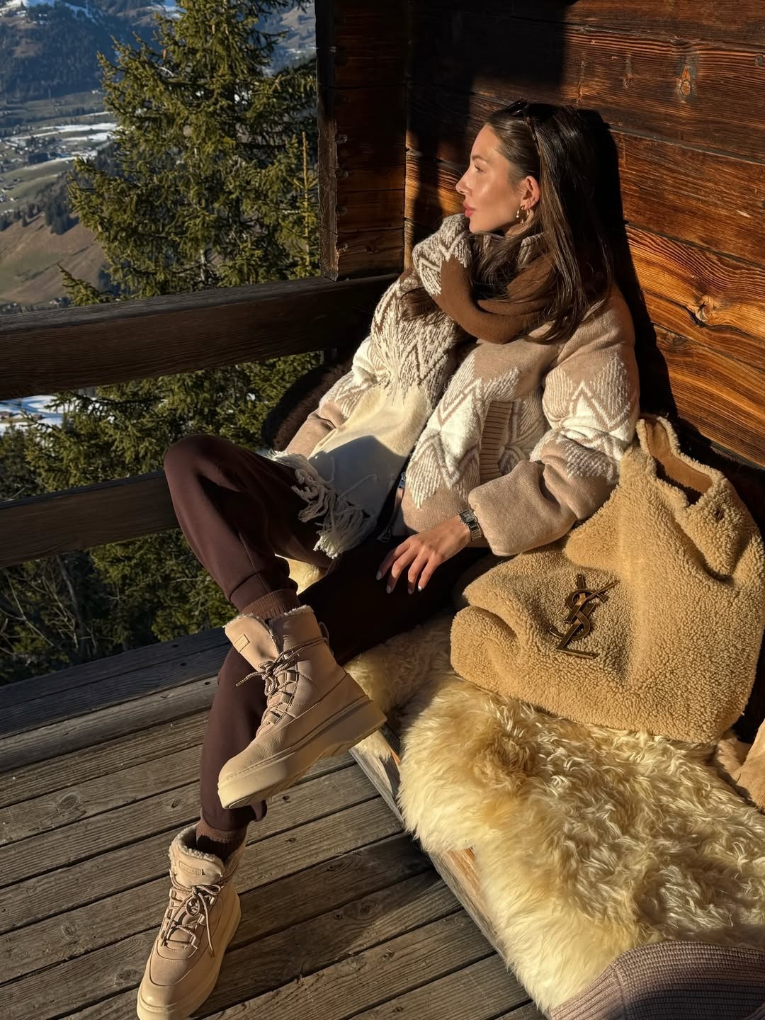 Woman wears argle knit jacket, leggings and snow boots with Saint Laurent Icare tote bag