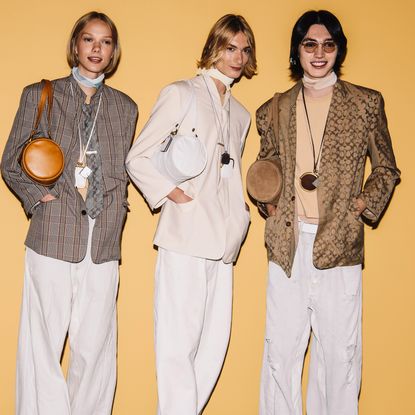 three models carrying the coach barrel bag in front of a plain wall