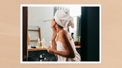 Portrait of a woman in a towel, looking into the mirror and applying body lotion 