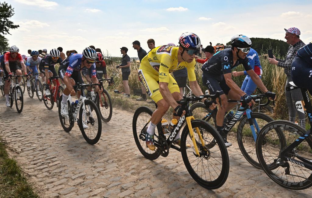JumboVisma teams Belgian rider Wout Van Aert R wearing the overall leaders yellow jersey cycles across a cobblestone sector with the pack of riders during the 5th stage of the 109th edition of the Tour de France cycling race 1537 km between Lille and Arenberg Porte du Hainaut in northern France on July 6 2022 Photo by Marco BERTORELLO AFP Photo by MARCO BERTORELLOAFP via Getty Images