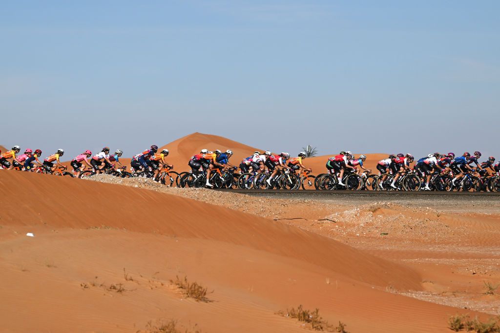 Peloton races by the sand dunes on stage 3 from Police Museum Al Ain to Jebel Hafeet at 2024 UAE Tour Women